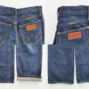 Op de afbeelding: Donkerblauwe Wrangler jeans van denim. De jeans hebben een klassiek ontwerp met vijf zakken, een bruine leren patch met het Wrangler-logo en een rechte pijp. De jeans worden vanuit meerdere hoeken getoond, inclusief de achterzakken en de opgerolde zoom.