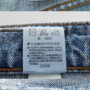 May include: Close-up of denim jeans labels. The labels show size details, including a waist measurement of 81 cm and a hip measurement of 98 cm. One label reads "Wrangler". Other labels provide care instructions.