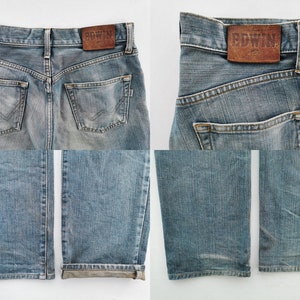 May include: Light blue denim jeans with a faded wash. The back features two pockets and a brown leather patch with the brand name "EDWIN". The jeans have a classic five-pocket design and a straight leg.