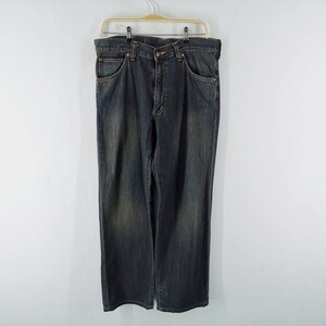 Peut inclure: Un jean en denim d&eacute;lav&eacute; fonc&eacute; suspendu &agrave; un cintre sur fond blanc. Le jean a une conception classique &agrave; cinq poches, une fermeture &agrave; bouton et &agrave; glissi&egrave;re, et une coupe droite. Le denim a un aspect d&eacute;lav&eacute; et us&eacute;.