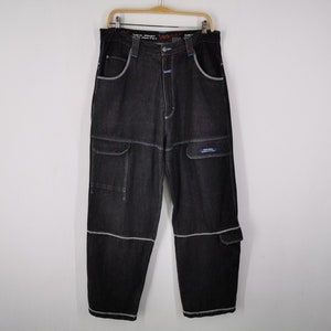 May include: Black denim cargo pants with white stitching and multiple pockets. The pants have a relaxed fit and are hanging on a wooden hanger. The pockets have a small blue and white label. The pants are a dark wash.
