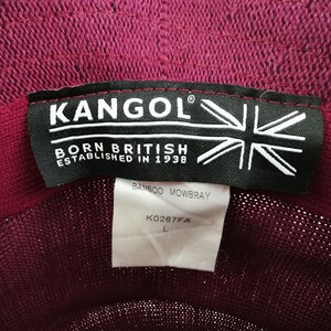 K&ouml;nnte beinhalten: Nahaufnahme des Etiketts eines bordeauxfarbenen Kangol-Hutes. Das Etikett lautet "KANGOL" &uuml;ber "BORN BRITISH ESTABLISHED IN 1938" mit einer Union-Jack-Grafik. Darunter steht "BAMBOO MOWBRAY" und "K0267FA L".