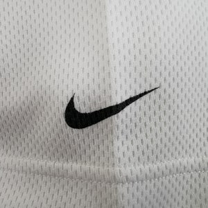 May include: Close-up of white athletic mesh fabric featuring a black Nike swoosh logo. The fabric has a textured, breathable design, and the logo is positioned in the upper right corner.