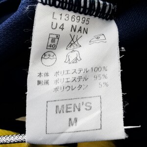 May include: A white clothing label with black text and symbols. The label shows the text "L136995", "U4 NAN", and "MEN'S M". It also includes washing instructions and fabric composition details.