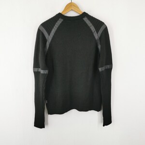 May include: Black sweater with faux leather accents on the shoulders and sleeves. The sweater is hanging on a wooden hanger against a white background. The sweater has a ribbed knit cuff and a crew neck.