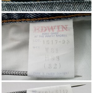 Op de afbeelding: Detail van een spijkerbroek met meerdere labels. Het hoofdlabel toont de merknaam "EDWIN" in rood op een gele achtergrond. Andere labels tonen maatdetails en wasvoorschriften. De spijkerbroek is blauw.