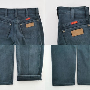 K&ouml;nnte beinhalten: Dunkelblaue Wrangler-Jeans mit klassischer Passform. Merkmale sind ein rotes Wrangler-Logo-Patch, ein braunes Leder-Patch und Metallnieten. Die Jeans hat ein gerades Bein und ein traditionelles F&uuml;nf-Taschen-Design.