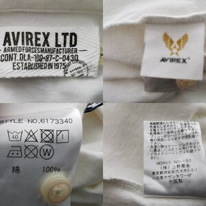 Puede incluir: Primer plano de una camisa blanca con varias etiquetas. Las etiquetas muestran la marca "AVIREX LTD" e incluyen texto como "ARMED FORCES MANUFACTURER" e instrucciones de lavado. La camisa tiene cierre de bot&oacute;n.