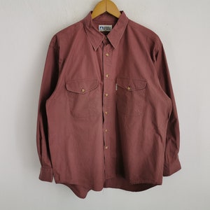 Puede incluir: Una taza de cerámica blanca con un asa negra y el texto "But First, Coffee" en negrita negra. La taza se encuentra sobre un fondo neutro, resaltando su diseño sencillo.