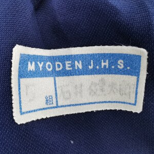 Puede incluir: Primer plano de una tela azul marino con una etiqueta blanca. La etiqueta dice "MYODEN J.H.S." en azul. Debajo, dos cuadros en blanco y un cuadro m&aacute;s peque&ntilde;o con caracteres japoneses.