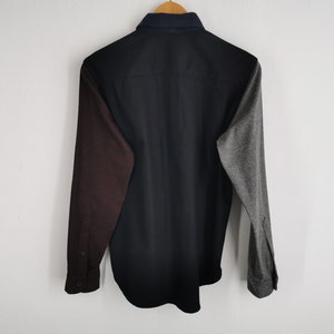 K&ouml;nnte beinhalten: Ein lang&auml;rmeliges Hemd mit Colorblock-Design. Das Hemd hat einen schwarzen K&ouml;rper, einen weinroten &Auml;rmel links und einen grauen &Auml;rmel rechts. Der Kragen ist marineblau.