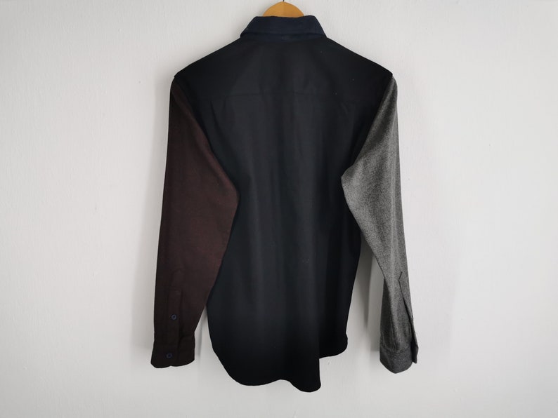 K&ouml;nnte beinhalten: Ein lang&auml;rmeliges Hemd mit Colorblock-Design. Das Hemd hat einen schwarzen K&ouml;rper, einen weinroten &Auml;rmel links und einen grauen &Auml;rmel rechts. Der Kragen ist marineblau.