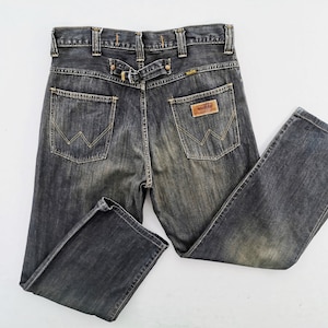 Peut inclure: Jean en denim d&eacute;lav&eacute; fonc&eacute; avec une conception classique &agrave; cinq poches. Comprend un patch en cuir et le logo Wrangler. Le jean a un d&eacute;tail de passant de ceinture &agrave; l'arri&egrave;re et un aspect d&eacute;lav&eacute;.