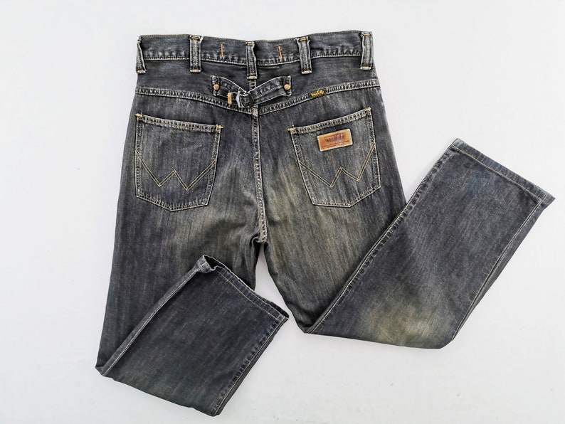 Peut inclure: Jean en denim d&eacute;lav&eacute; fonc&eacute; avec une conception classique &agrave; cinq poches. Comprend un patch en cuir et le logo Wrangler. Le jean a un d&eacute;tail de passant de ceinture &agrave; l'arri&egrave;re et un aspect d&eacute;lav&eacute;.