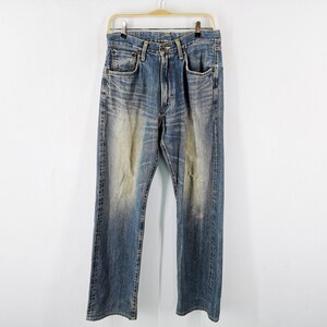 May include: Blue denim jeans with a faded wash and distressed details, hanging on a wooden hanger. The jeans have a classic five-pocket design and a straight leg fit. The fabric shows signs of wear.