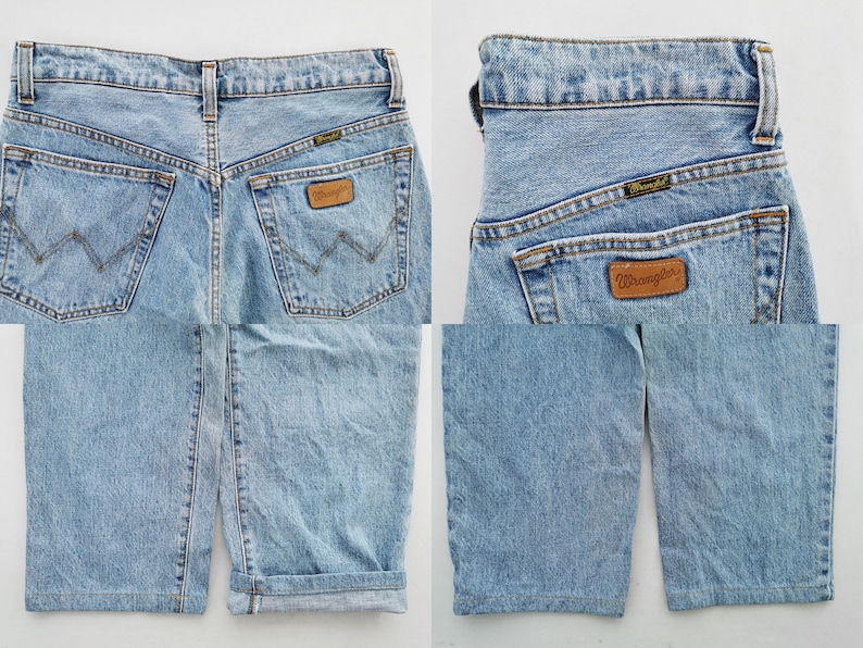 May include: Light blue denim Wrangler shorts. The shorts have a classic five-pocket design, a brown leather Wrangler patch, and a Wrangler label on the back pocket. The shorts have a cuffed hem.