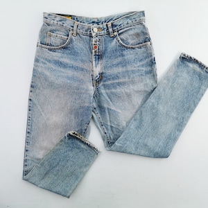 Op de afbeelding: Lichtblauwe denim jeans met een vervaagde wassing. De jeans heeft een knoop- en ritssluiting, een klassiek vijf-zakken ontwerp en een rechte pijp. De jeans ligt plat op een witte ondergrond.