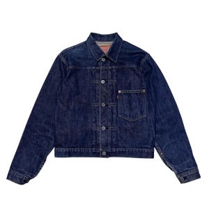 Op de afbeelding: Een witte keramische mok met een zwart handvat en de tekst "But First, Coffee" in een zwarte, handgeschreven lettertype. De mok staat op een wit oppervlak.