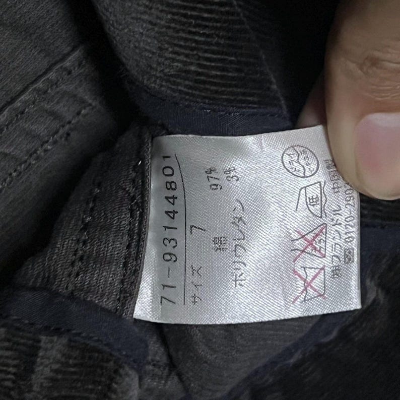 May include: A close-up shot of a clothing label with Japanese text and numbers. The label is white with black text and displays the numbers "71-93144801" and "7". The fabric composition is 97% cotton and 3% polyurethane.
