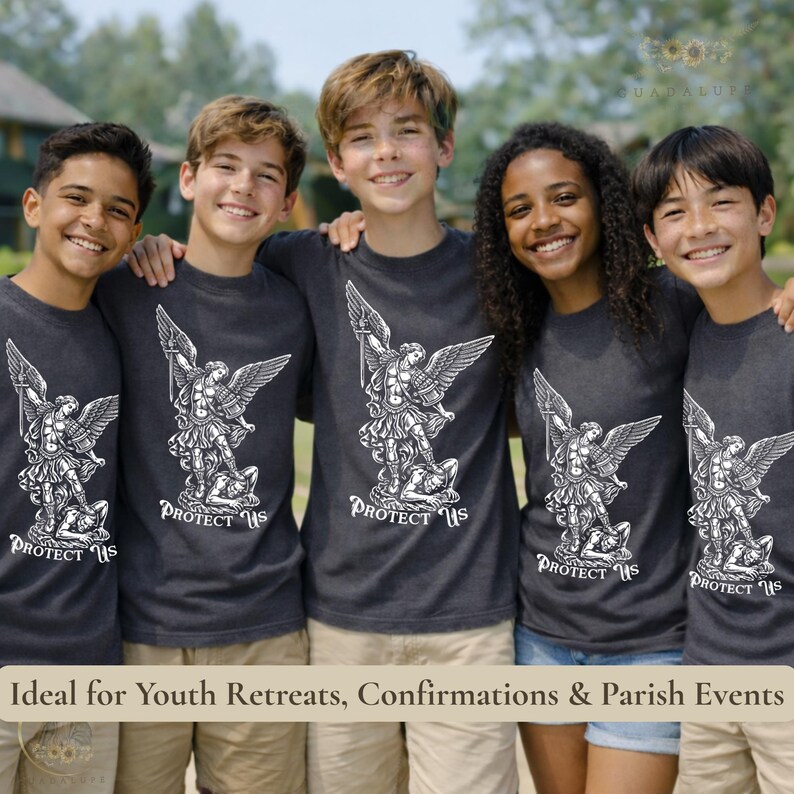 May include: Five smiling people wearing dark gray t-shirts with a white graphic of an angel slaying a demon, with the text "PROTECT US" below. The image is taken outdoors.