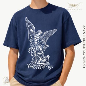 May include: Navy blue t-shirt featuring a white graphic of an angel with a sword, standing over a figure. The text "PROTECT US" is below the graphic. The shirt is labeled "UNISEX - YOUTH TRUE NAVY".