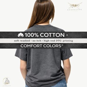 May include: A charcoal gray t-shirt made of 100% cotton, with the text "100% COTTON" and "COMFORT COLORS&reg;" printed on it. The shirt is soft-washed and features high-end DTG printing. The shirt is worn by a person.