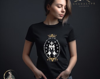 May include: A black short-sleeved t-shirt featuring a white graphic of the Miraculous Medal symbol, including a cross, the letter M, and two hearts, surrounded by the text O Mary, Conceived Without Sin, Pray for Us Who Have Recourse to Thee.