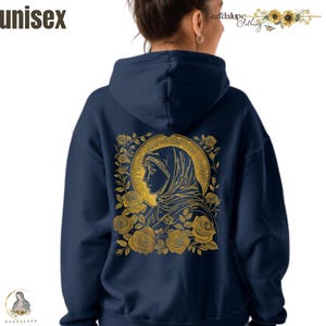 May include: Navy blue unisex hoodie featuring a gold illustration of a religious figure surrounded by roses. The text "unisex" is at the top left. The back of the hoodie has a gold illustration of a religious figure with the text "Guadalupe Clothing".