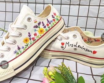 May include: A pair of white canvas sneakers with embroidered flowers and the text "Mrs. Levinson" on one shoe. The shoes have red hearts and a red stripe around the edge.