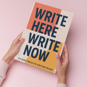 May include: A book titled "WRITE HERE WRITE NOW" is held by two hands against a pink background. The book has a cream-colored background with orange and yellow blocks. The text is in navy blue and reads "WRITE HERE WRITE NOW" and "A 7-DAY CREATIVE WRITING GUIDE."