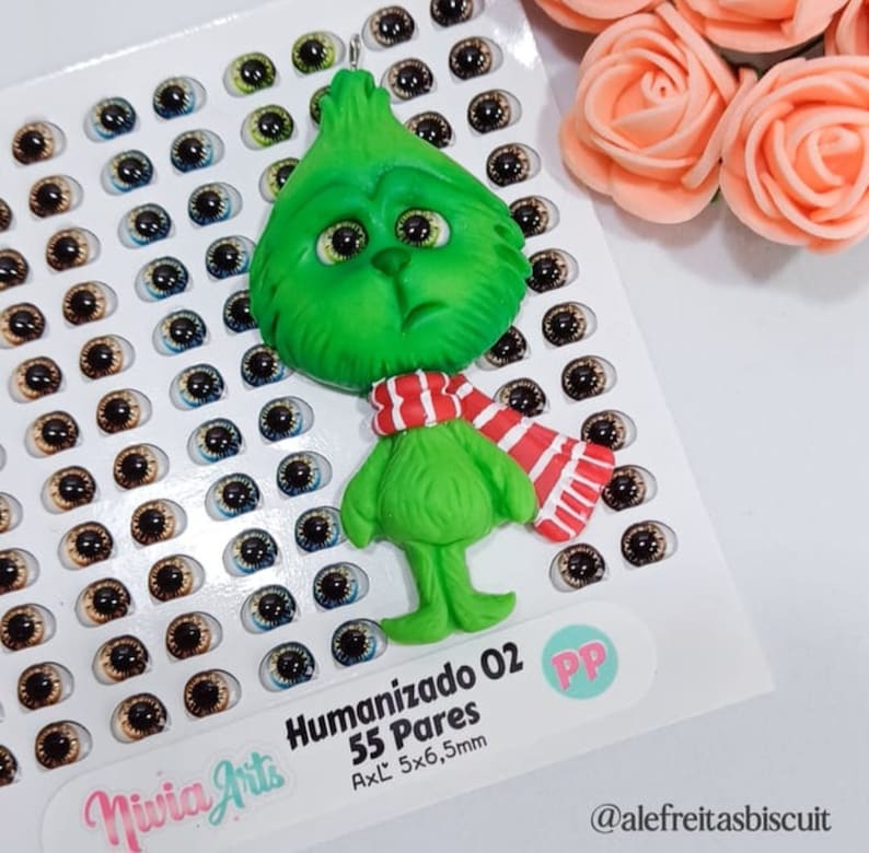 May include: Green Grinch character made of polymer clay with a red and white striped scarf. The Grinch is 5.5 cm wide and 6.5 cm tall. The image also shows a sheet of 55 pairs of plastic doll eyes in various colours.