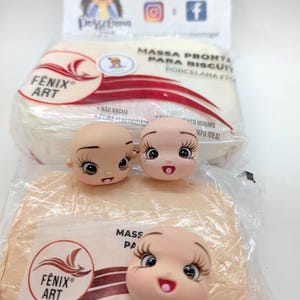 May include: Image of craft supplies, including two packages of Fenix Art clay and three doll faces. The doll faces are painted with eyelashes, eyebrows, and rosy cheeks. The clay packages have text in Portuguese.