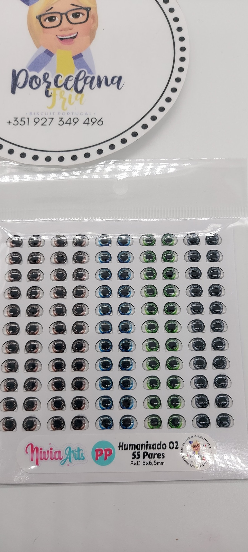 May include: A sheet of 55 pairs of doll eyes, with a variety of colours, including brown, blue, green, and grey. The eyes are 5 mm by 6.5 mm in size. The sheet is labelled "Humanizado 02" and "Niwia Arts PP".