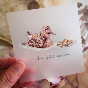 May include: A watercolor illustration of a mother duck with a pink bow on her head and two ducklings. The text "Mon petit canard" is written below the ducks.