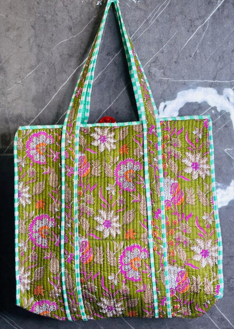 May include: A green quilted tote bag with a floral print and white and green gingham trim. The bag has two long handles.