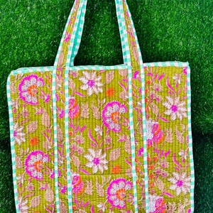 May include: A green quilted tote bag with a floral print and white and green gingham trim. The bag has two straps.