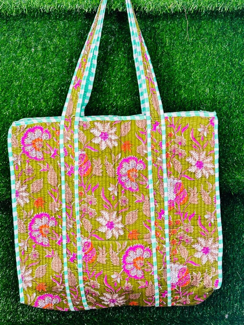 May include: A green quilted tote bag with a floral print and white and green gingham trim. The bag has two straps.