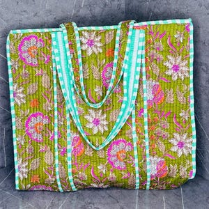 May include: A green quilted tote bag with a floral print and white and green striped handles.