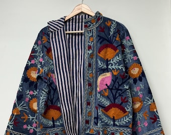 May include: A denim blue jacket with intricate floral embroidery in orange, pink, and red. The jacket features a striped lining and is displayed on a wooden hanger. The embroidery details are visible on the sleeves and front.