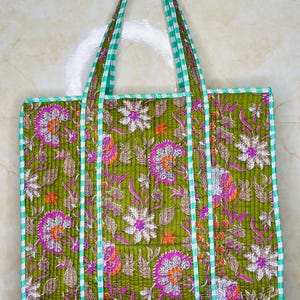 May include: A green quilted tote bag with floral print and white and green gingham trim. The bag has two straps.