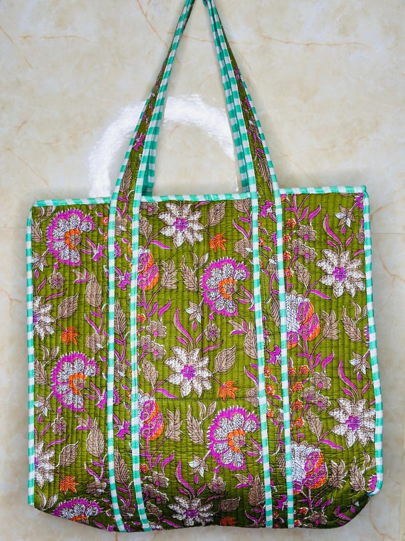 May include: A green quilted tote bag with floral print and white and green gingham trim. The bag has two straps.