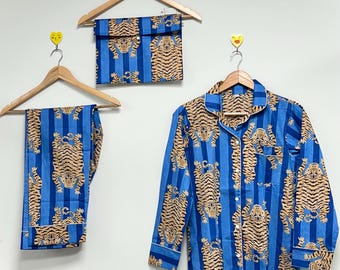 Puede incluir: Conjunto de pijama azul con estampado de tigre. El conjunto incluye una camisa abotonada de manga larga, pantalones y una bolsa a juego. El pijama presenta rayas azules verticales y un patrón repetido de tigres color canela.