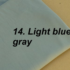 Puede incluir: Una muestra de tela gris azul claro con el texto "14. Gris azul claro" impreso en ella.