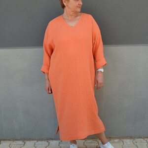 Puede incluir: Un vestido largo, holgado, de color coral con cuello en V y mangas 3/4. El vestido est&aacute; hecho de una tela suave y texturizada y tiene un ajuste holgado.