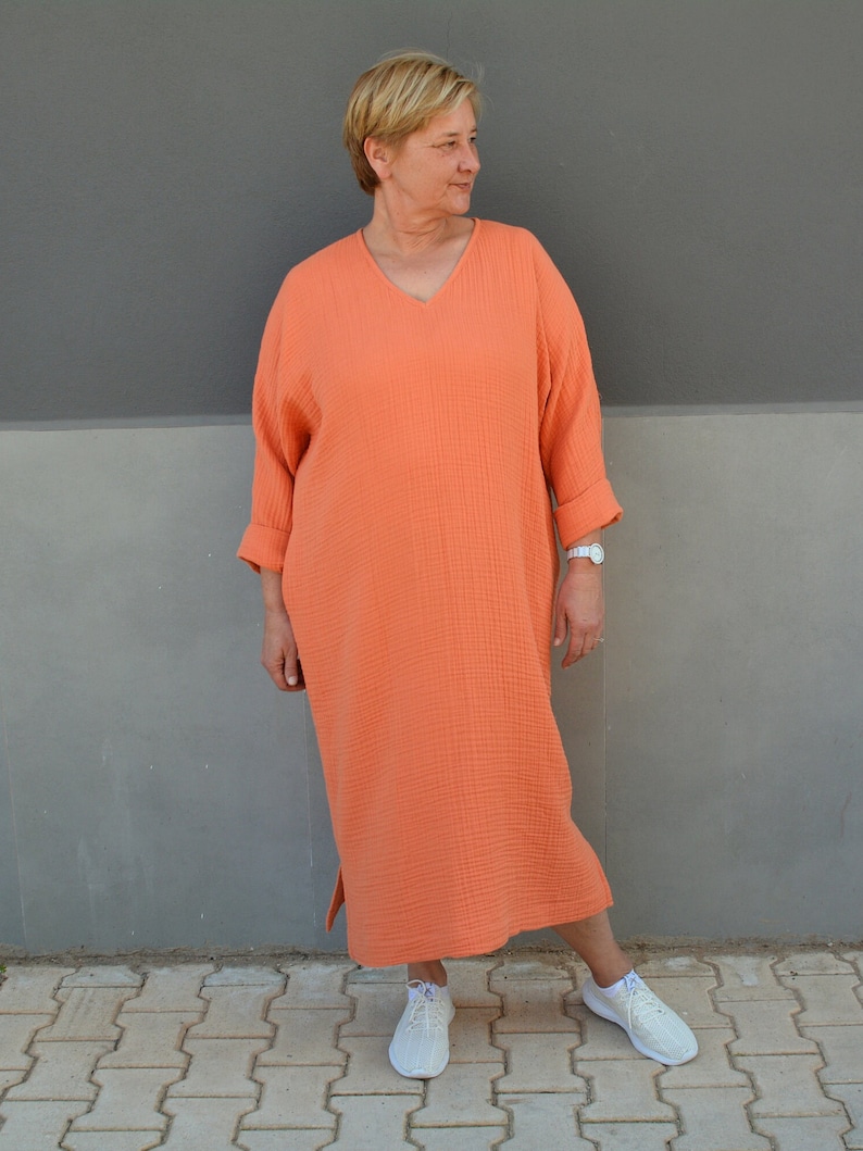 Puede incluir: Un vestido largo, holgado, de color coral con cuello en V y mangas 3/4. El vestido est&aacute; hecho de una tela suave y texturizada y tiene un ajuste holgado.