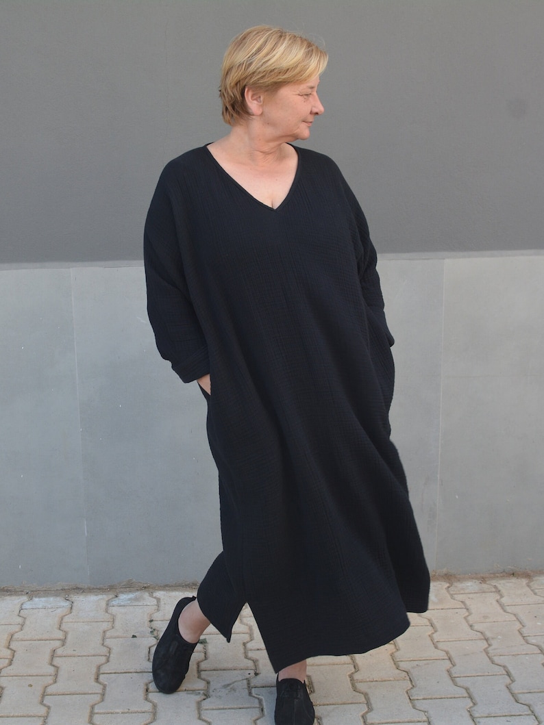 Puede incluir: Un vestido negro de manga larga con cuello en V. El vestido est&aacute; hecho de una tela suave y texturizada y tiene un corte holgado.