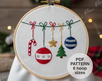 May include: Embroidered Christmas ornaments in a wooden hoop. The design includes a candy cane, a star, a Christmas tree, and two baubles. The ornaments are suspended from a green string with red and gold bows. The text "PDF PATTERN 6 hoop sizes" is in a white circle.