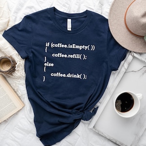 May include: A navy blue t-shirt with white text that reads "if (coffee.isEmpty()) { coffee.refill(); } else { coffee.drink(); }"
