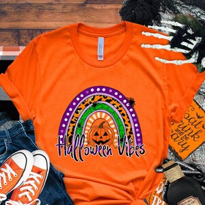 May include: Orange t-shirt with a rainbow design featuring a pumpkin and the text "Halloween Vibes".