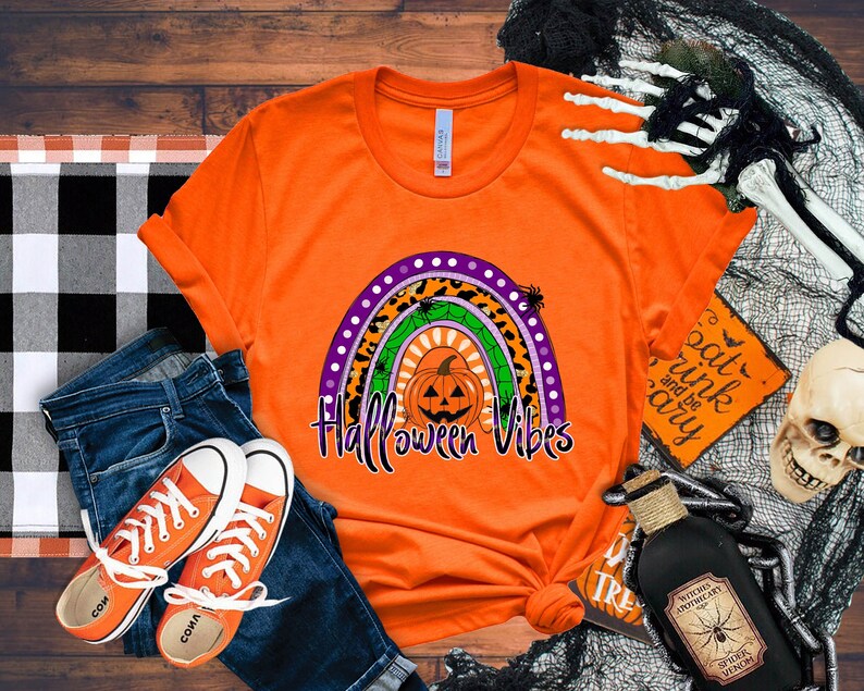 May include: Orange t-shirt with a rainbow design featuring a pumpkin and the text "Halloween Vibes".